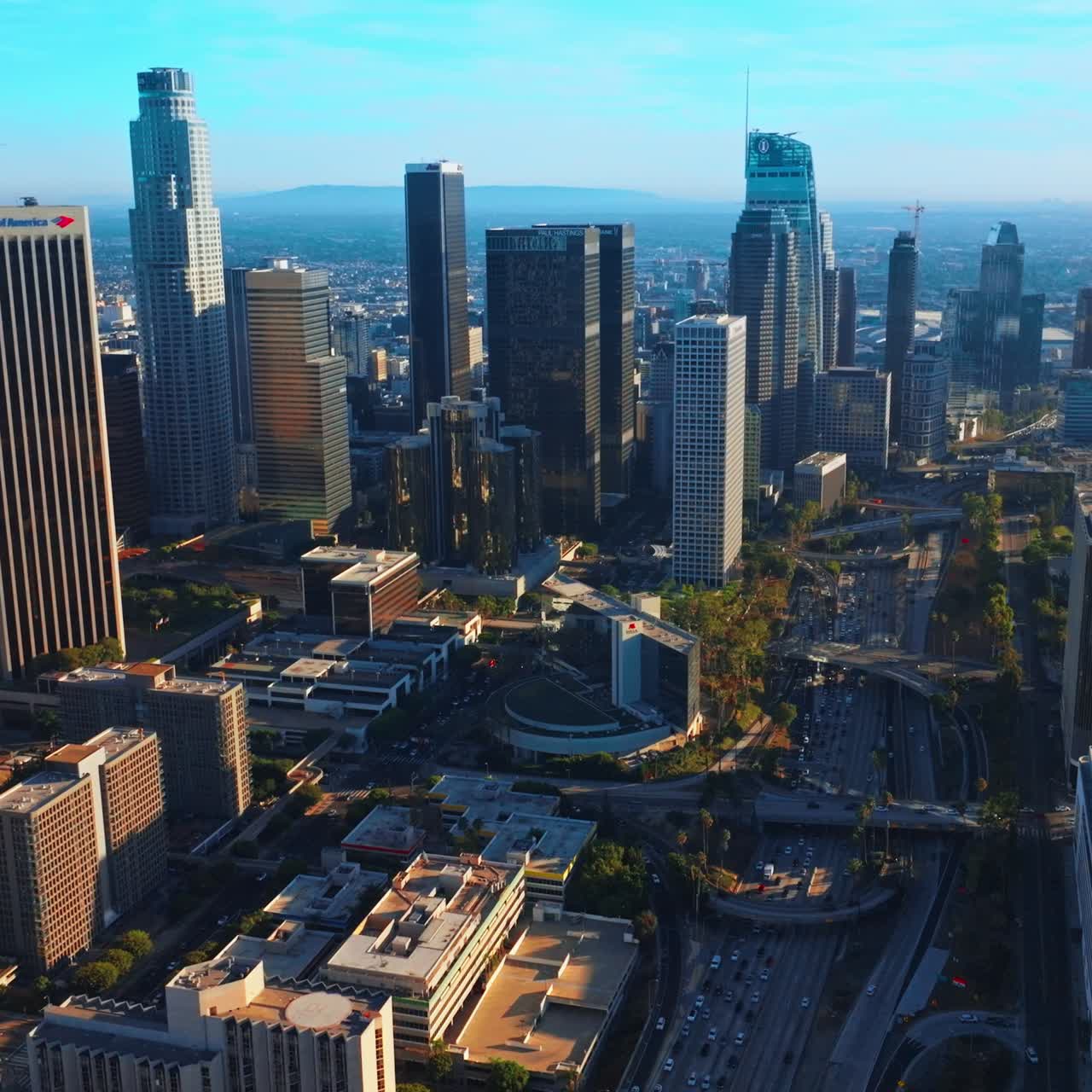 Approaching the beautiful modern skyscrapers of contemporary Los Angeles. Lively downtown at sunny daytime from aerial perspective