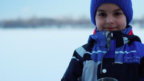 winter child with hot drink. boy face with termos