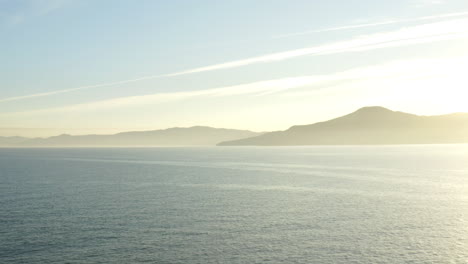 beautiful aerial drone view sunset over the ocean and mountains on the horizon