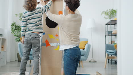 kids and mom creating a cardboard rocket