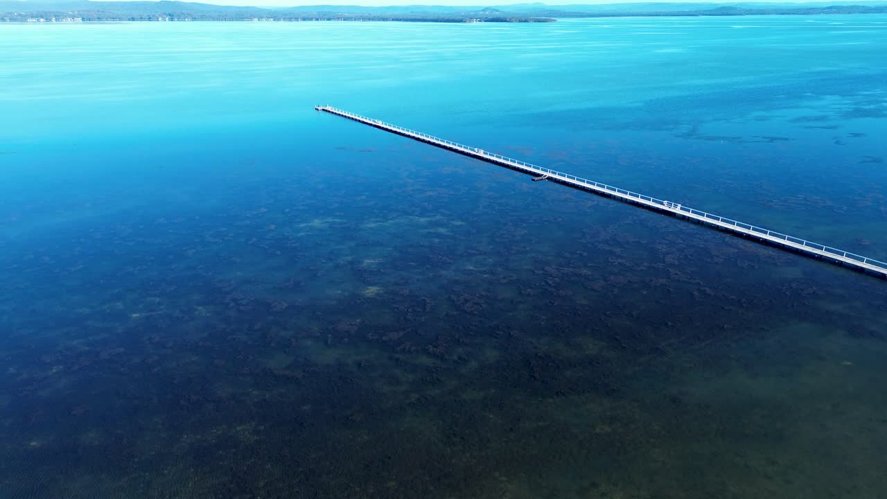 Drone aerial landscape of Long Jetty timber pier boardwalk wharf dock waterfront in Tuggerah lake seaweed river inlet water catchment Central Coast Australia travel holidays tourism reservoir