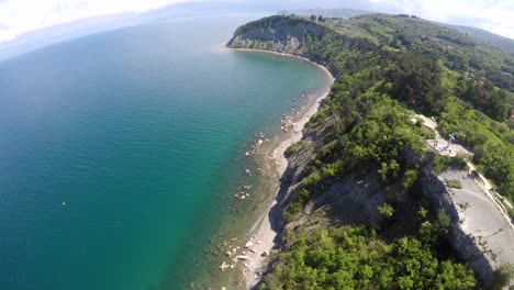 a drone shot, flying over a rocky beach, near a cliff