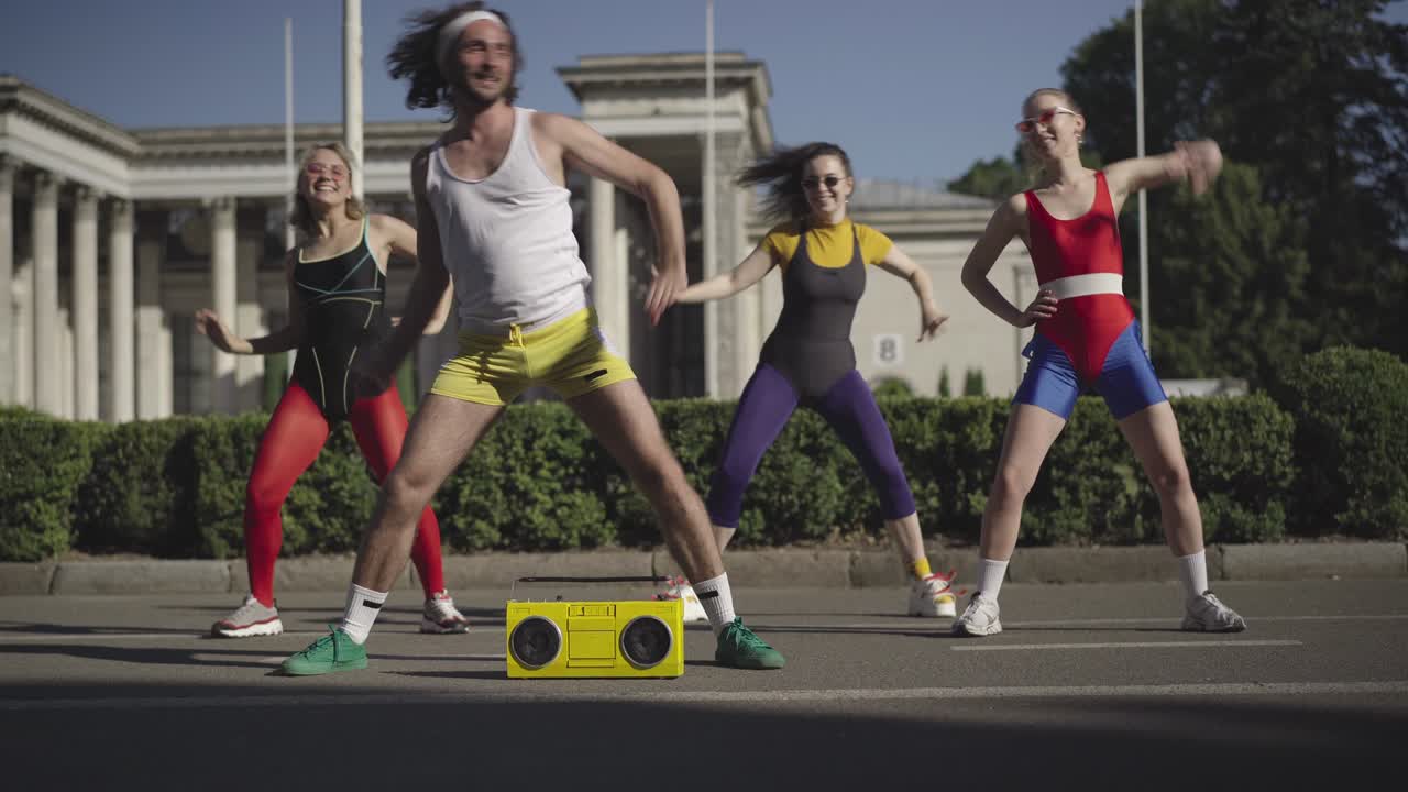 amplio tiro de deporte de baile en la década de 1980 al aire libre. hombre y mujer caucásicos en forma positiva entrenando para la música discoteca en la calle soleada de la ciudad de verano y sonriendo. estilo de vida vintage y concepto divertido.