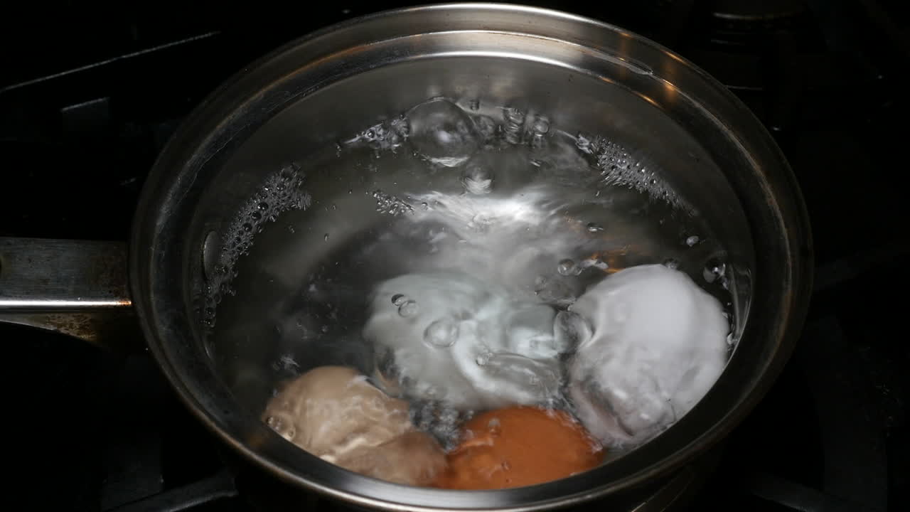 Four eggs boiling inside a small pot full of water