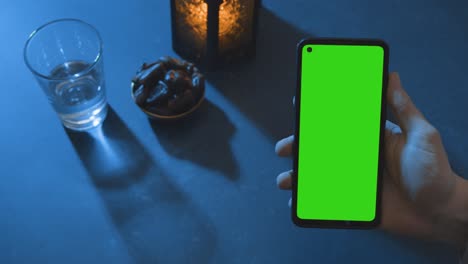 wide shot of lantern dates and water with a green screen phone at dusk