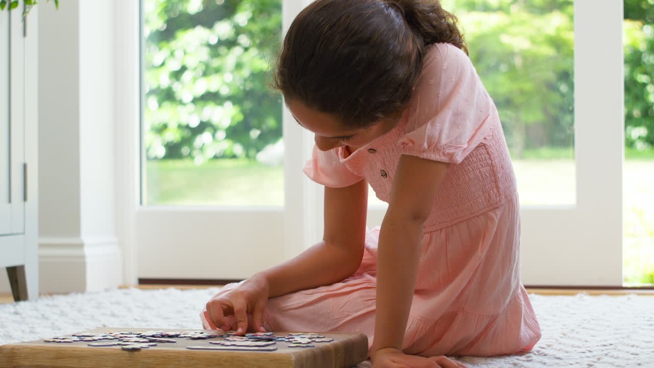 집에서 라운지의 바닥에 앉아 있는 소녀가 퍼즐을 하고 있습니다.