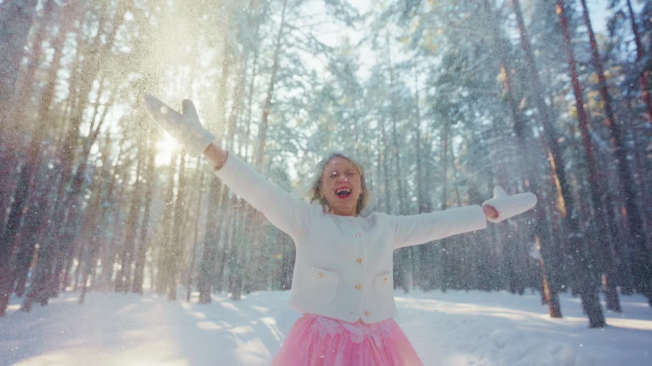 Nadšená dívka si užívá padající sníh v slunečném zimním lese