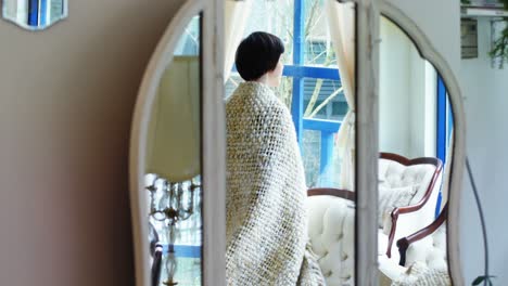 Woman-looking-through-window-in-living-room