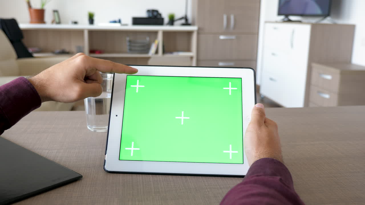 녹색 화면을 가진 태블릿을 사용하는 사람