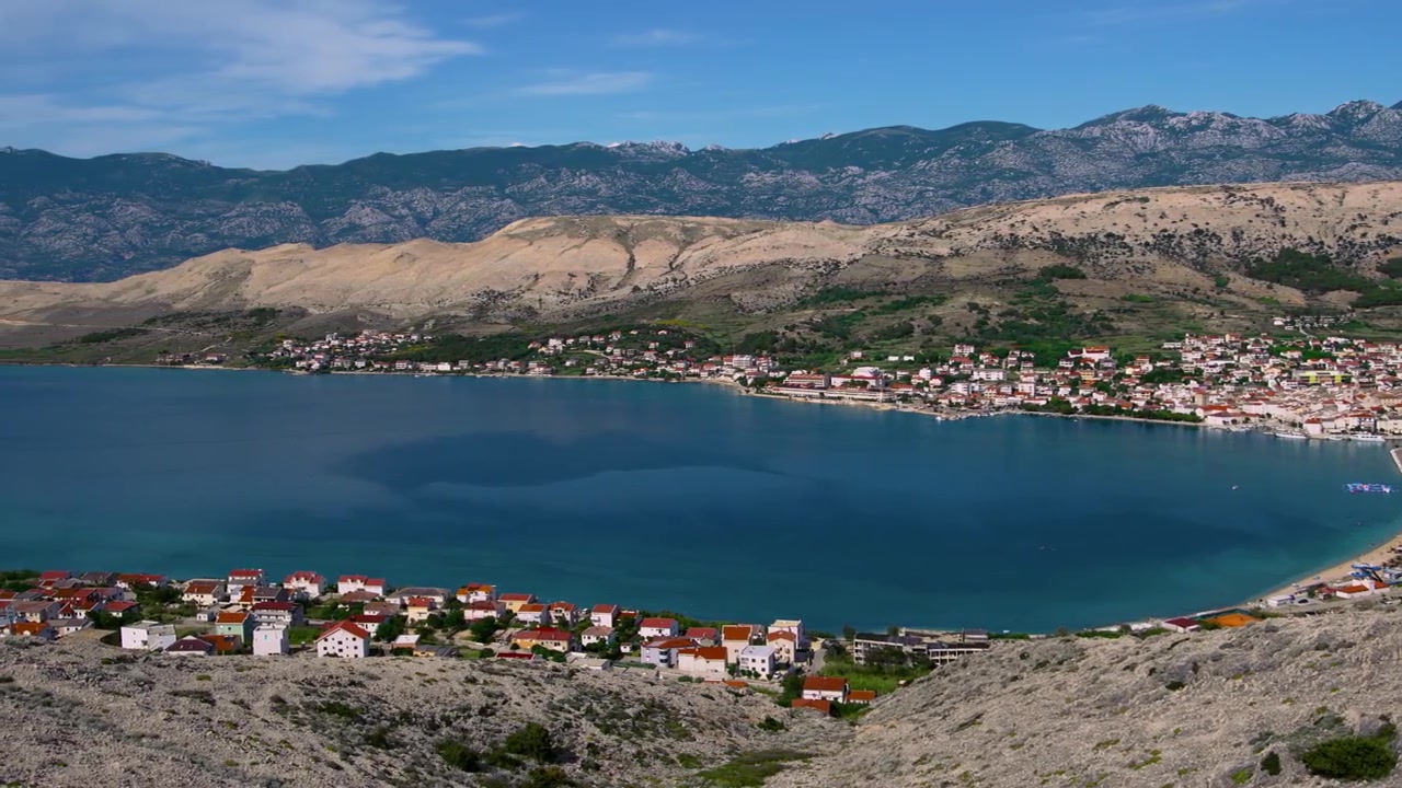 Kaunis Pagin saaren kaupunginlahti rantaviivalla, suola-altailla ja Velebit-vuorilla Kroatiassa. Kameran panorointi.