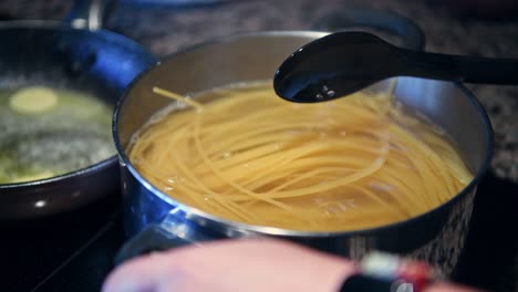 cooking spaghetti in boiling water with a spoon