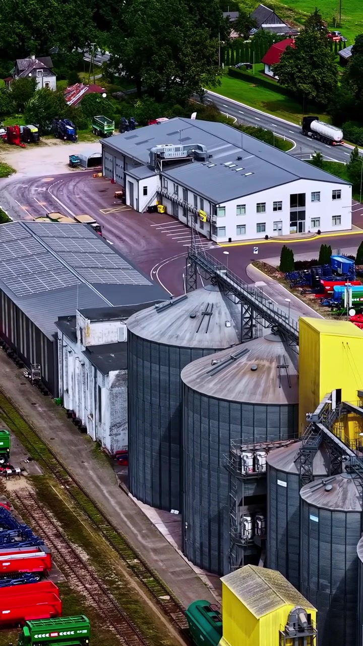 Getreidesilos, Förderanlagen, Hofverkehr und Verarbeitungsgebäude auf einem landwirtschaftlichen Industriestandort, vertikale filmische Luftansicht