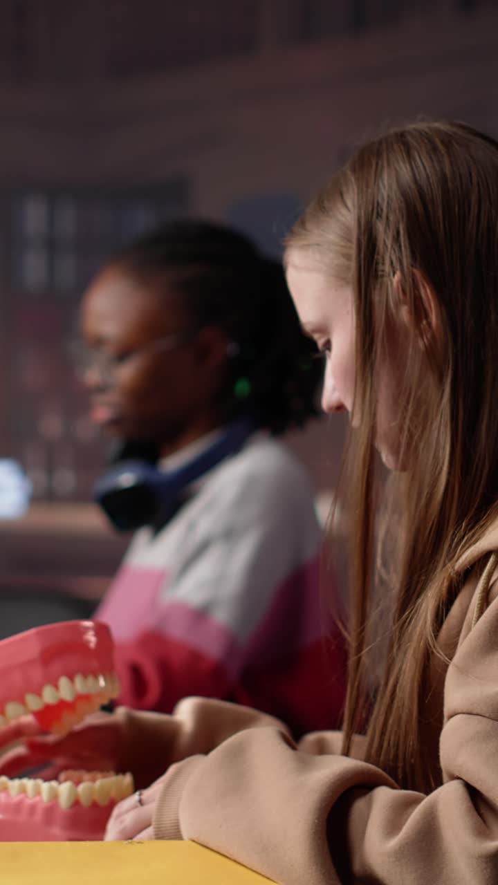 Vertical video african american future dentist examines a plastic model of human teeth