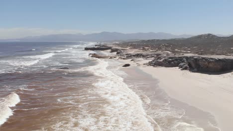 aerial: garden route coast of south africas western cape with red algae in water