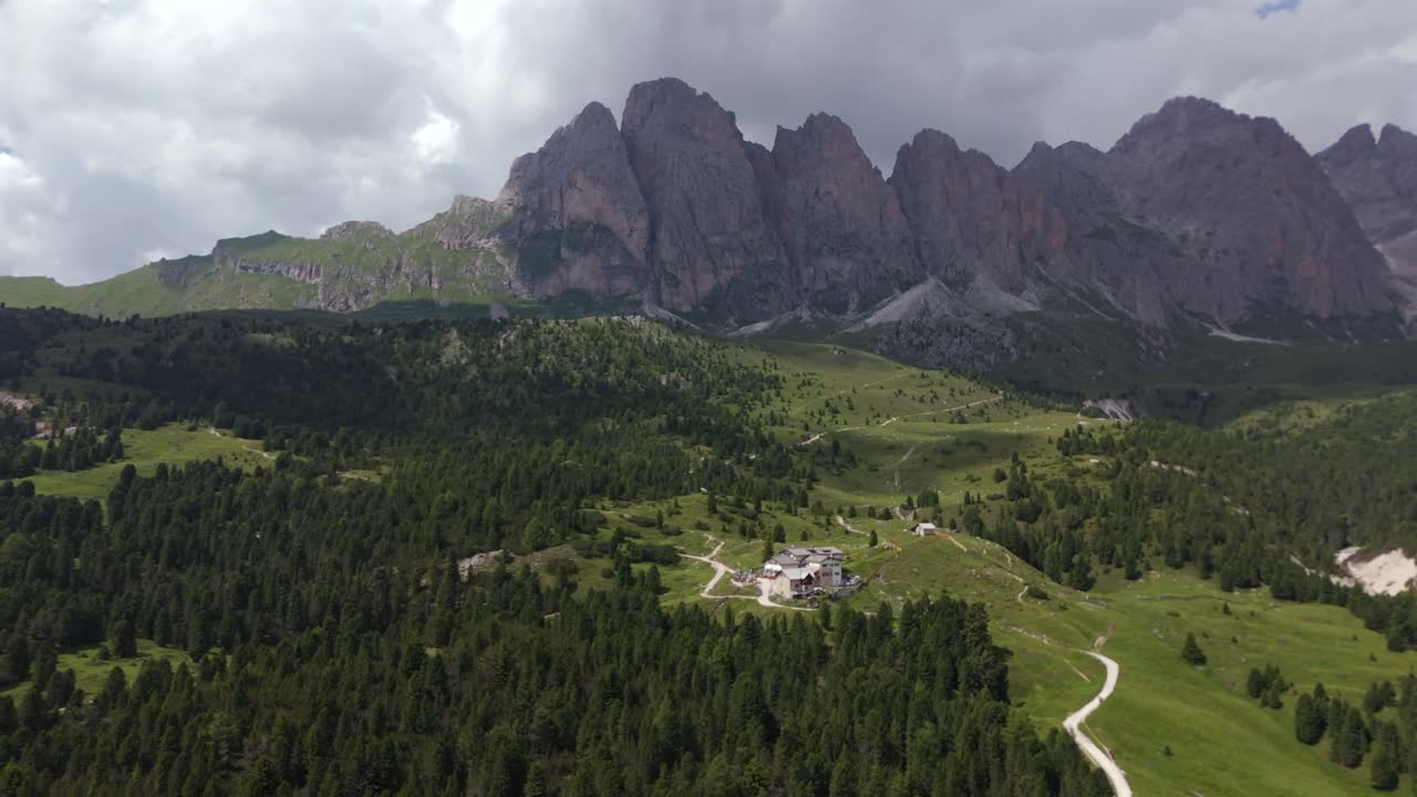 captadora vista aérea de regensburger hütte ubicada en medio de densos bosques, con los dramáticos picos de las dolomitas que se elevan en el fondo, ofreciendo un retiro idílico en el corazón de la naturaleza