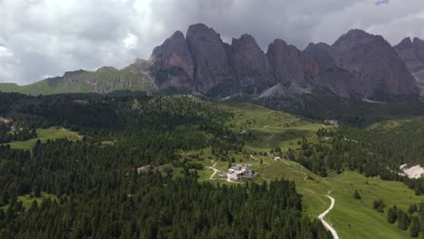 captivating aerial view of regensburger hütte nestled amidst dense forests, with the dramatic peaks of the dolomites towering in the background, offering an idyllic retreat in the heart of nature