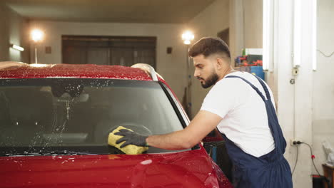 man washing a red car