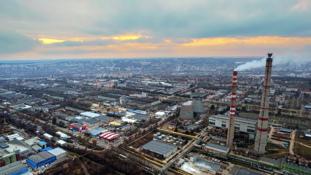 Aerial drone timelapse view of thermal power plant in Chisinau at cloudy weather, Moldova. View of pipes with felling steam, cityscape, sunset