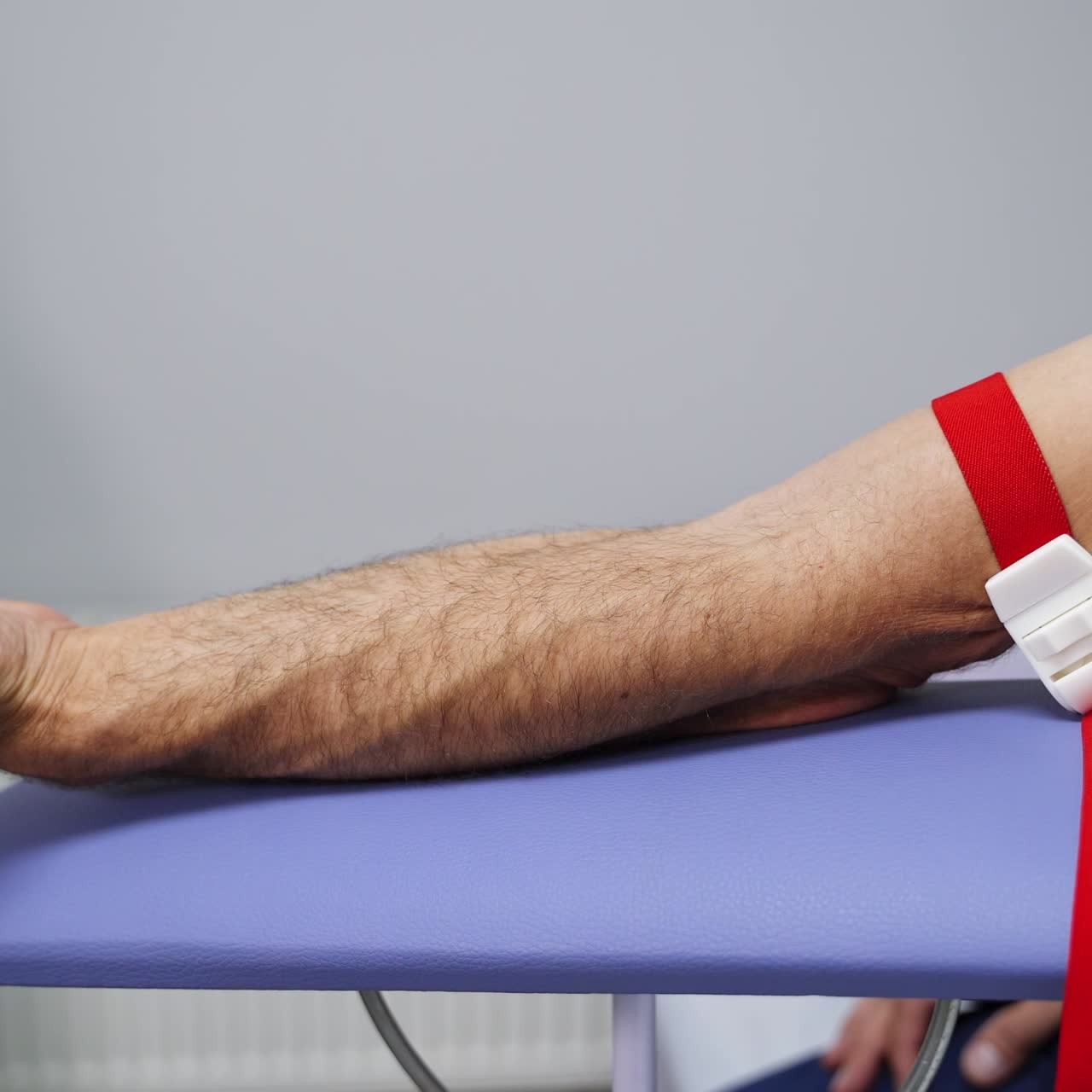 Male hand in a medical tourniquet making fist. Nurse preparing to take blood sample of a patient