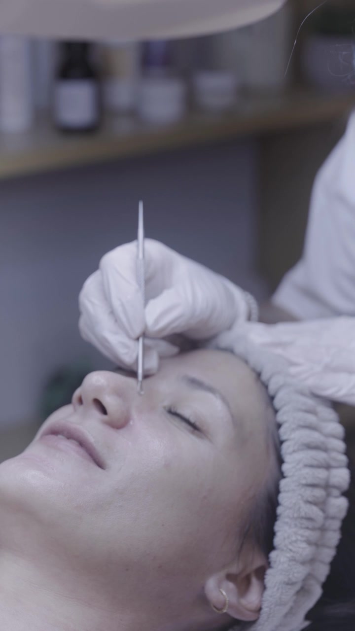 Fin borste som applicerar serum på avslappnad hud under en ansiktsritual