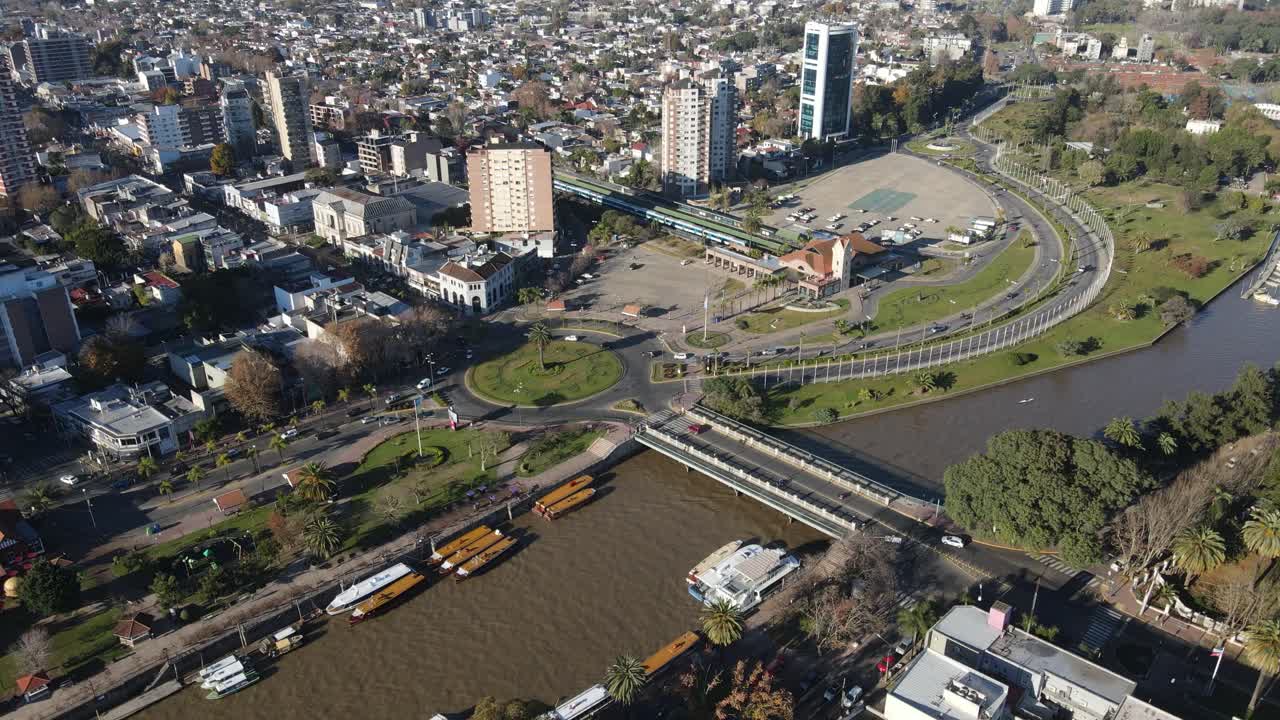 vuelo aéreo que muestra el paisaje urbano de tigre con barcos de atraque en el río primero y tráfico en la rotonda durante la puesta de sol