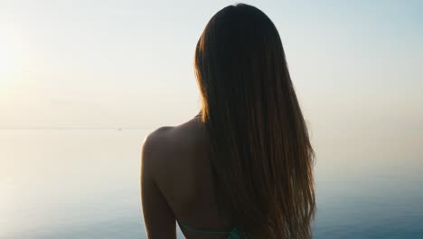 una joven bonita tomando fotos con su teléfono inteligente al atardecer en la playa cerca del mar en vacaciones. cámara lenta
