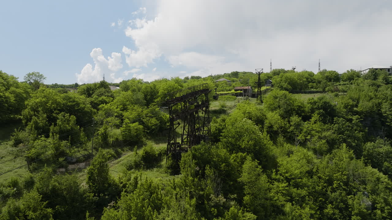 pilón de teleférico de material oxidado y contenedor colgante en la ladera cubierta de hierba