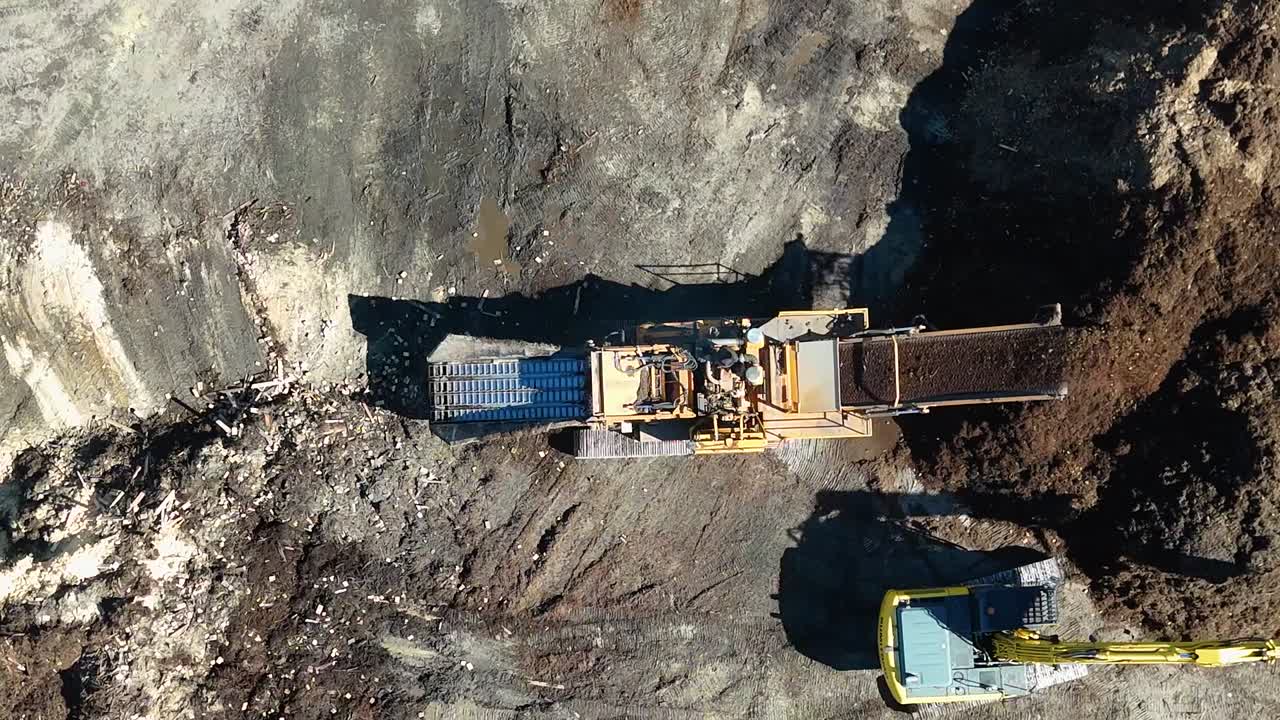 High angle drone shot showing heavy machinery processing organic material at an industrial worksite