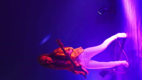 vertical video of a woman playing bass guitar in a studio dancing and looking at the camera