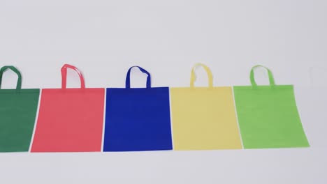 video of row of multi coloured canvas bags with copy space on white background