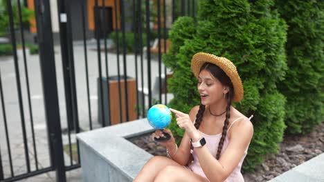 woman playing with a model globe in a city park