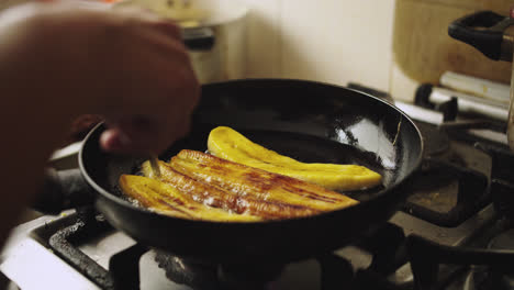 close-up of a pan frying sweet ripe plantains with oil over high heat