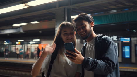 young couple using smartphone and waving at a subway station