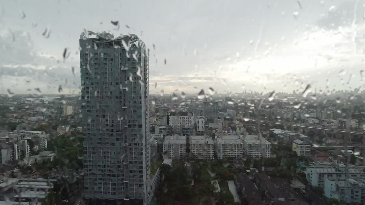 la lluvia cae por la ventana. vista aérea. la lluvia fuera de la ventana de la sala de estar en la temporada de lluvias en bangkok, tailandia. la ventana exterior está borrosa por la lluvia del edificio de la ciudad y la carretera y el cielo.