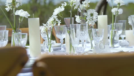 elegant wedding reception table setup with clear glassware, candles, and floral decor. static shot
