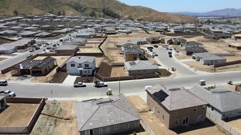 Die-Drohne-Gleitet-über-Eine-Belebte-Baustelle-Auf-Der-Spring-Mountain-Ranch-Am-Flussufer,-Eingerahmt-Von-Halbfertigen-Häusern-Und-Einigen-Fertiggestellten-Wohnhäusern