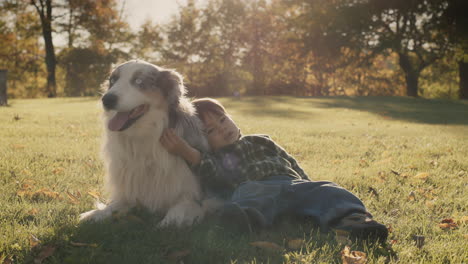 a two-year-old is lying on the lawn next to a large dog. friendship and pet concept