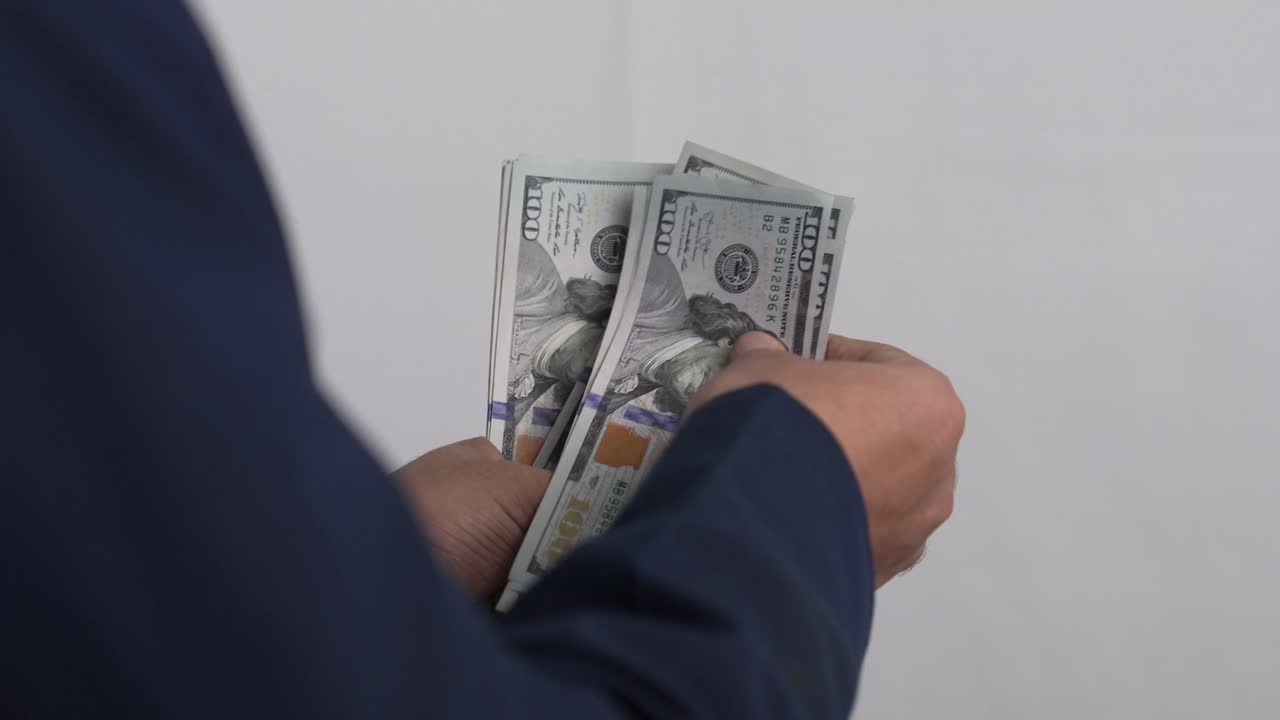 Primo piano di mani che contano banconote di dollari americani, finanza e gestione del contante. Video 4K