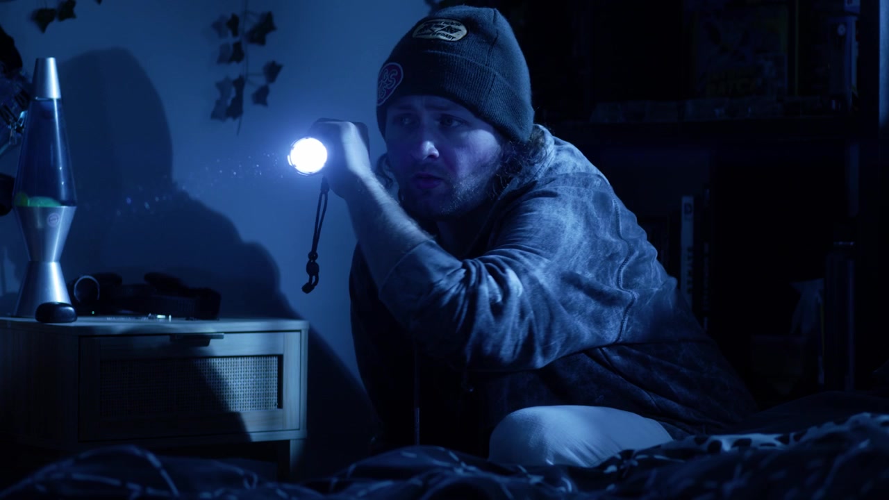 Ripresa cinematografica anamorfica in 4K di un uomo che cerca in una camera da letto illuminata dalla luna con una torcia, mentre drammatici bagliori dell'obiettivo attraversano l'inquadratura, creando un'atmosfera di tensione e orrore