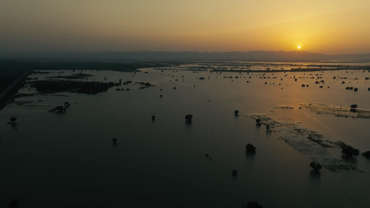 Expansive floodwaters from River Sutlej covering the landscape in Bahawalpur, Punjab at sunset