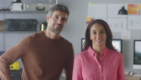 portrait of smiling businessman and businesswoman working in creative office