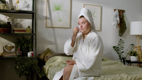 young woman applying lotion on her face