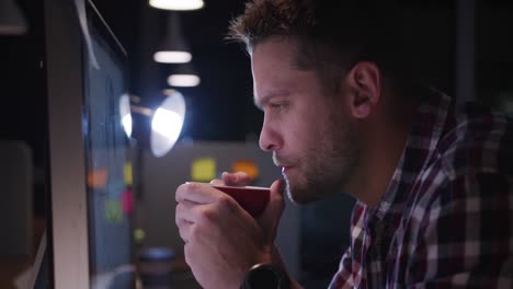 Businessman-drinking-coffee-and-working-in-a-modern-office-by-night