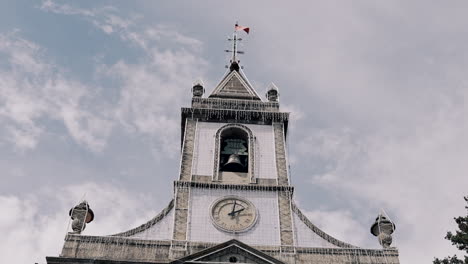 gothic tower church with clock and bell, cloudy sky