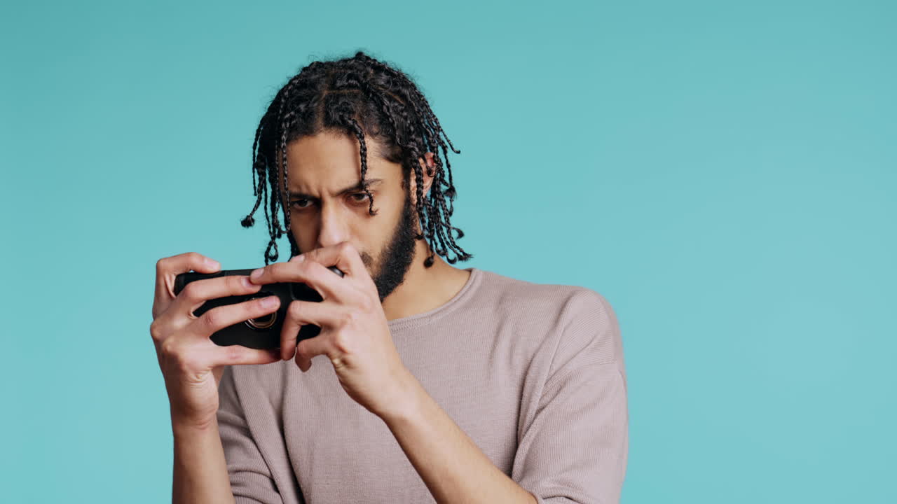 hombre en silla de ruedas jugando videojuegos en el teléfono móvil, celebrando la victoria, estudio