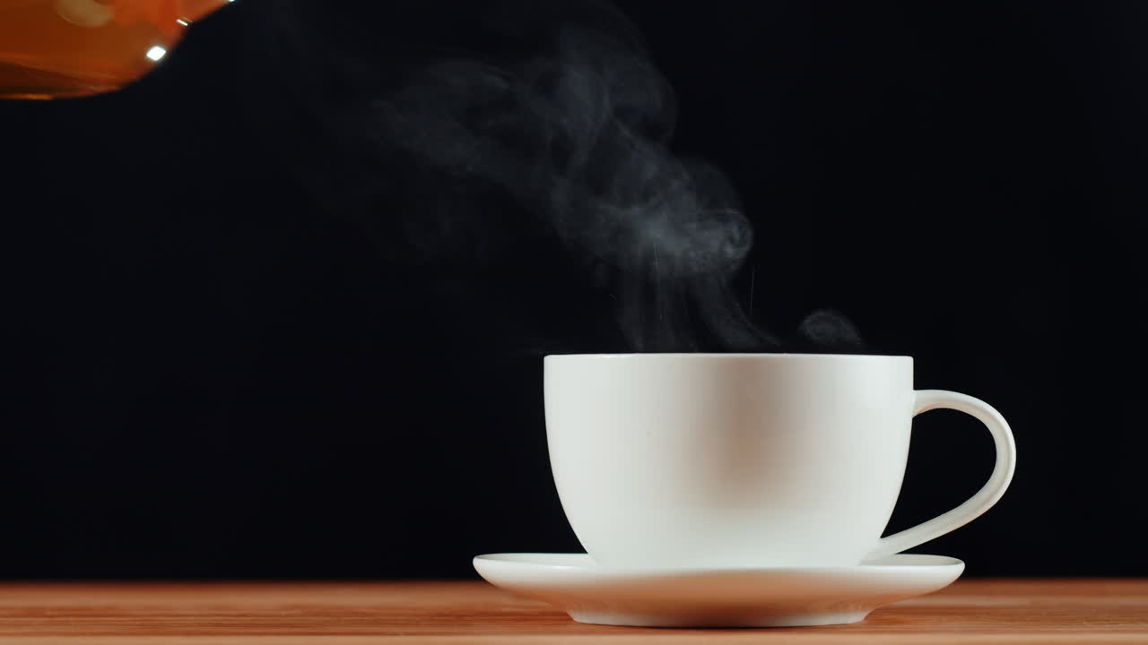 Pouring hot tea into a white cup
