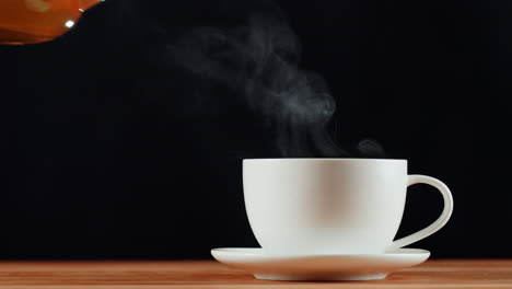 pouring hot tea into a white cup
