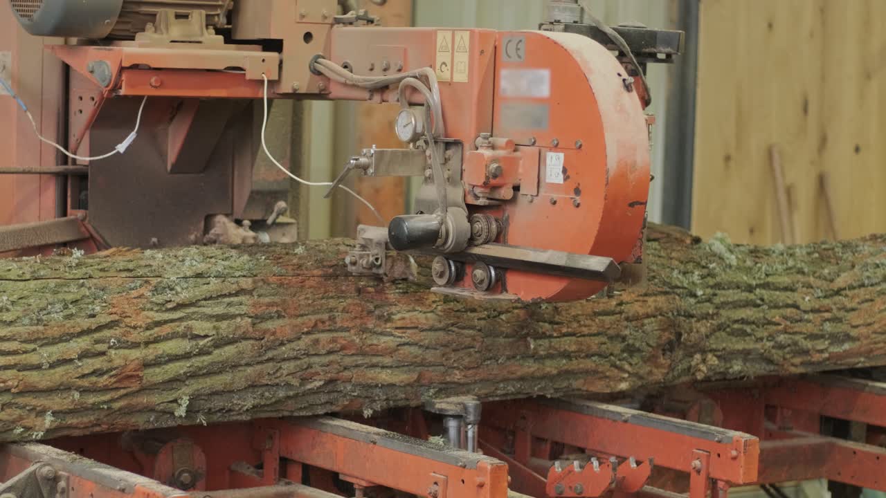 Machine industrielle écorçant une grande bille dans une scierie