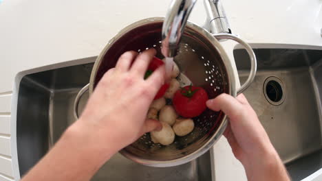 point of view of man washing vegetables in a colander