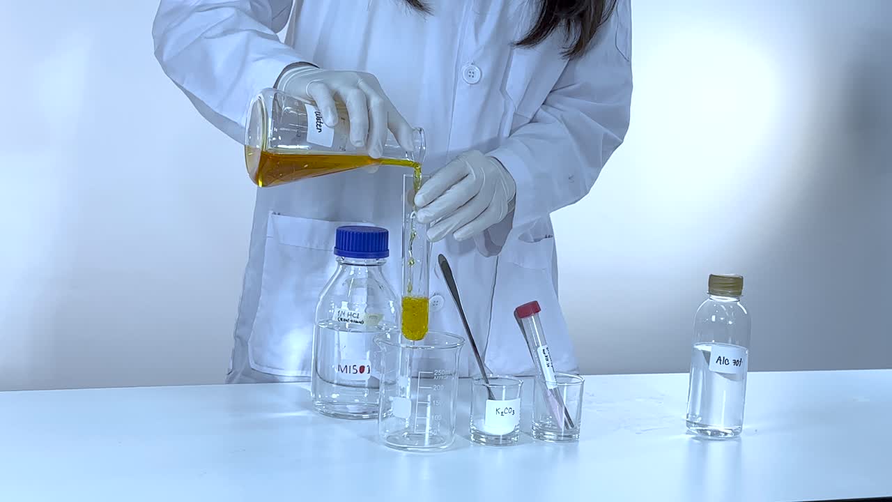 Scientist conducts potassium carbonate experiment, pouring liquid into beaker. Controlled laboratory environment with bright lighting